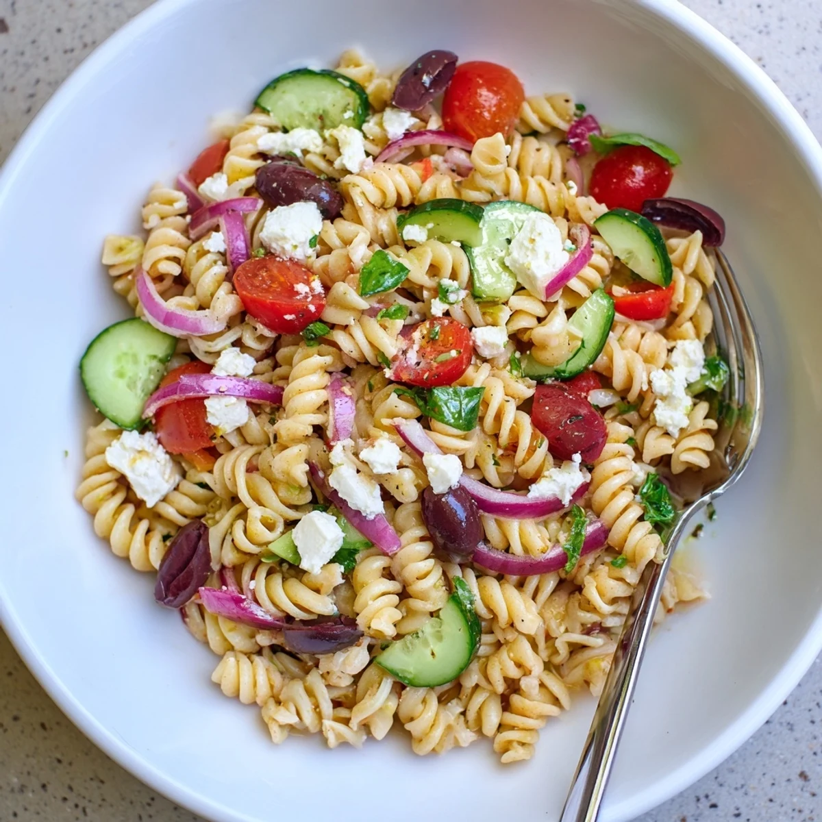 Mediterranean Olive Oil and Feta Pasta Salad, a colorful mix of pasta, olives, and fresh tomatoes.