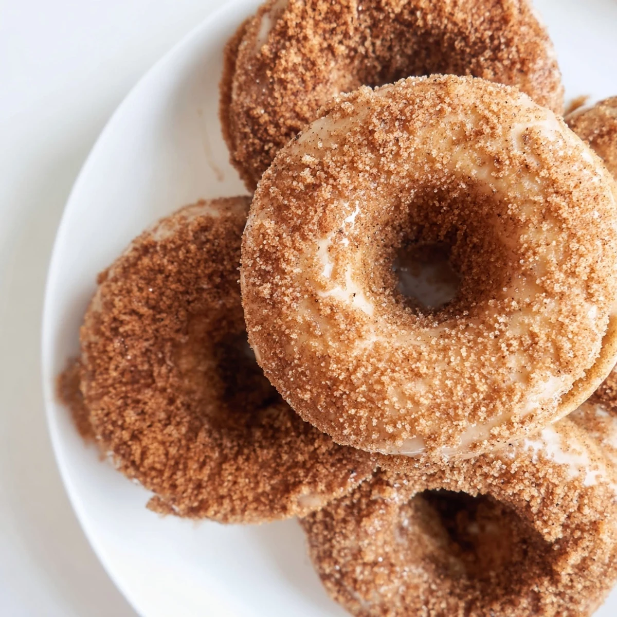 Warm, freshly-baked cinnamon-sugar donuts glistening with sweet coating, a perfect American dessert.