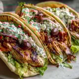 Mediterranean Chicken Gyros with Creamy Feta Tzatziki stacked in a pita with lettuce, tomato, and olives. 