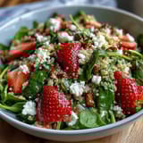 A colorful bowl of strawberry feta quinoa salad with juicy berries, creamy cheese, and fresh greens drizzled with balsamic dressing.