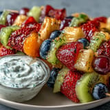 Colorful rainbow fruit skewers with honey-yogurt dip, a healthy and vibrant snack perfect for parties and summer gatherings.