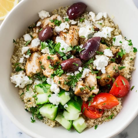 Vibrant Mediterranean Chicken Bowl with juicy grilled chicken, chickpeas, feta, and olives over fluffy quinoa, topped with fresh cucumbers, tomatoes, and zesty lemon-oregano dressing.