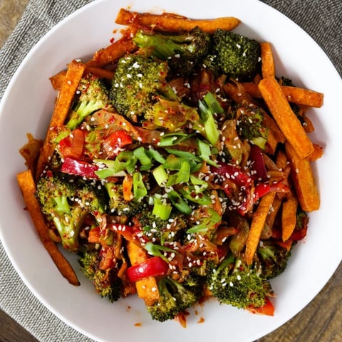 Bright orange sweet potato matchsticks and crisp broccoli florets fill a wok for this Comforting Fermented Veggie Winter Stir-Fry, garnished with green onions and sesame seeds.
