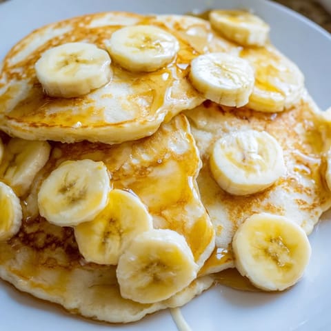 Stack of fluffy weekend golden-brunch banana pancakes ready to be enjoyed with fresh banana slices.