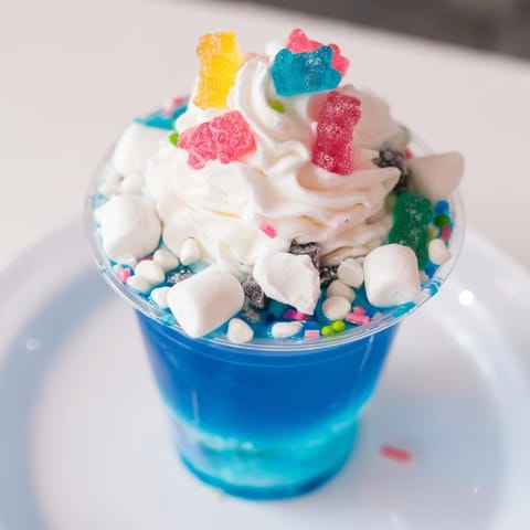 Colorful snow globe Jello cups, piled high with marshmallows and festive sprinkles, ready to be enjoyed.