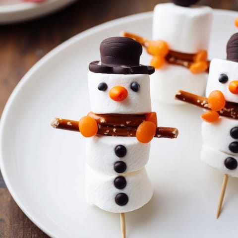 Close-up of a festive marshmallow snowman stick scene, with pretzel arms, awaiting eager eaters.