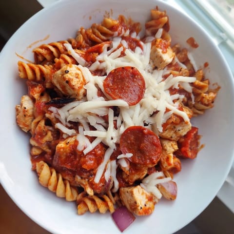 This warm photo reveals a bubbling skillet of One-Pan Pizza Pasta, ready to serve with pepperoni.