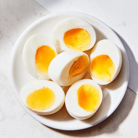 Golden yolks peek from peeled Air Fryer Boiled Eggs, ideal for a quick, protein-packed breakfast, prepared simply.