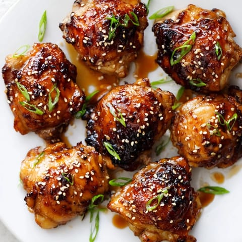 Freshly baked Honey Garlic Glazed Chicken thighs feature caramelized, sticky skin and a savory glaze, served alongside steamed rice and vibrant stir-fried vegetables.