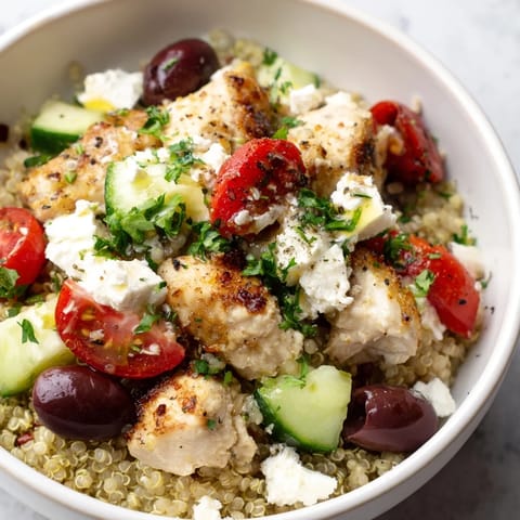 Colorful Mediterranean Chicken Bowl featuring golden chicken, creamy feta, Kalamata olives, crisp veggies, and quinoa, drizzled with tangy lemon-oregano dressing, perfect for a healthy lunch.