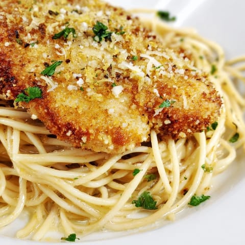 A close-up of Brown Butter Lemon Chicken Pasta highlights nutty brown butter, melted Parmesan, and vibrant parsley on spaghetti and juicy chicken strips.