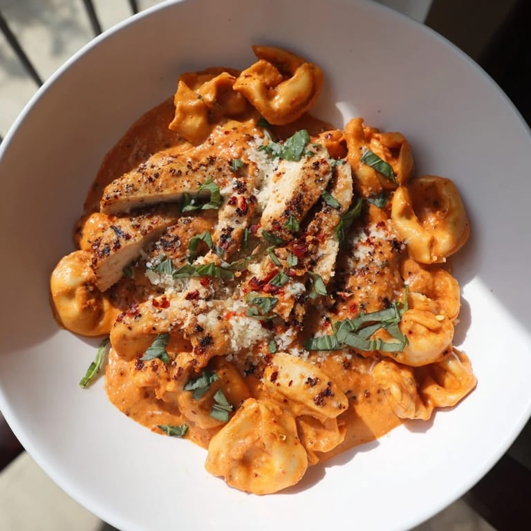 Close-up of golden, sliced chicken nestled in rich sauce with Marry Me Chicken Tortellini.