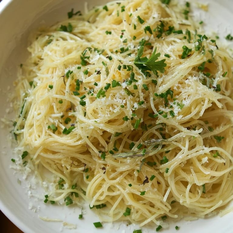 Steaming bowl of Lemon Capellini topped with fresh herbs, a light and elegant Italian dish.