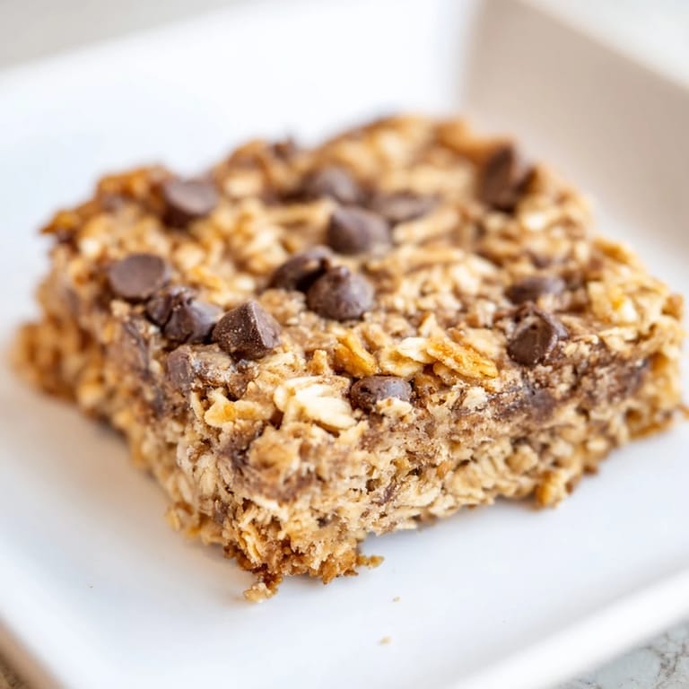 Square of warm Baked Oats That Taste Like Cake, speckled with chocolate chips, ready to slice and enjoy.