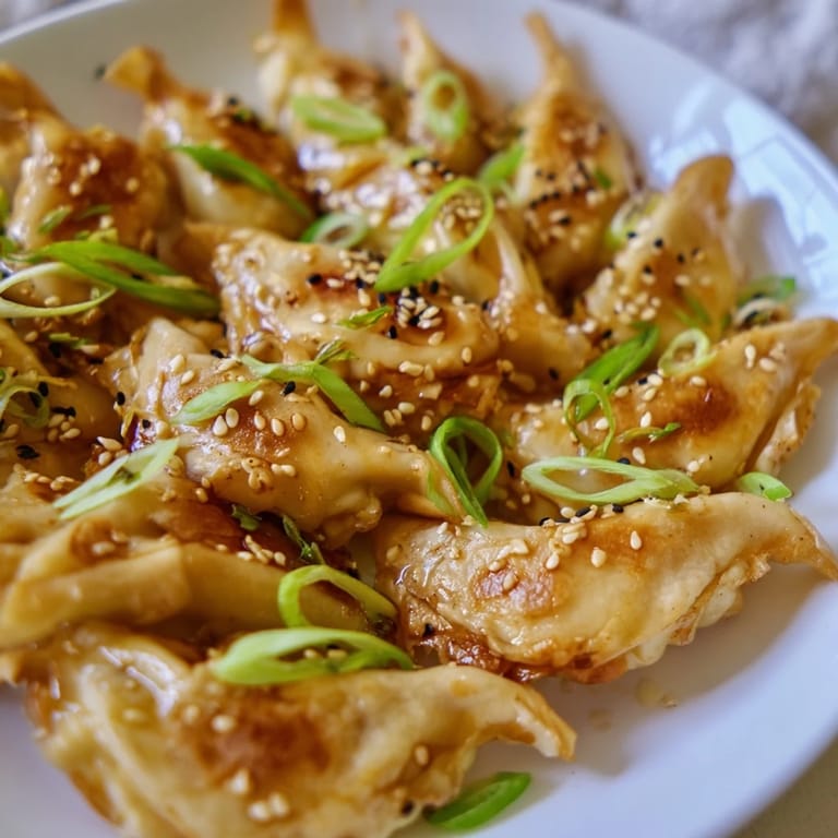 Golden brown Air Fryer Frozen Dumplings, garnished with sesame seeds and green onions for extra flavor.