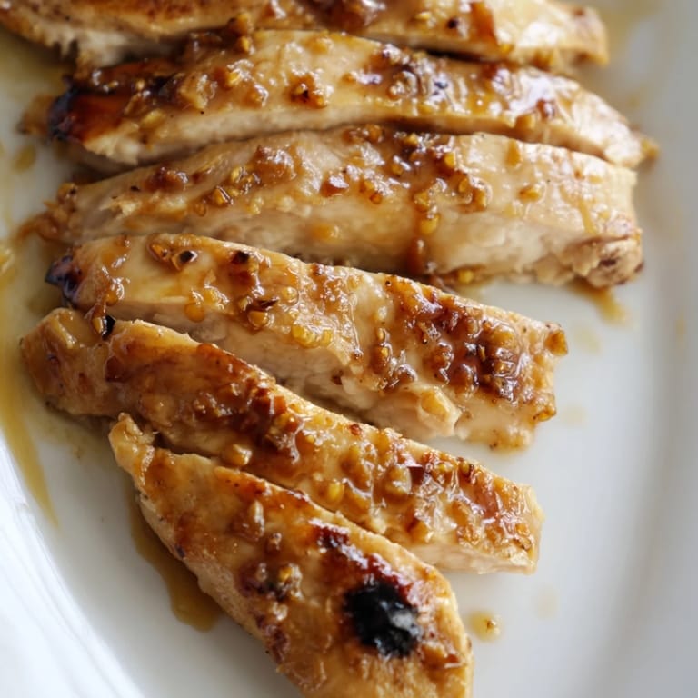 A close-up of a sliced Honey Mustard Chicken Wrap showing layers of seasoned chicken, crisp lettuce, and tangy honey-mustard dressing on a whole wheat tortilla.