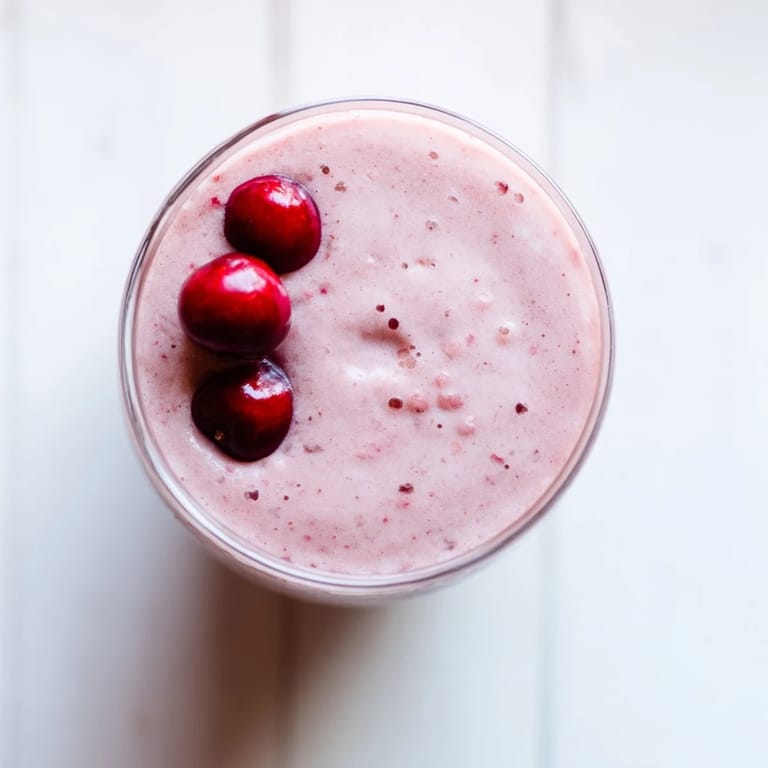 Cherry Almond Smoothie poured into a glass, showing thick, frosty consistency and a drizzle of maple syrup on top.